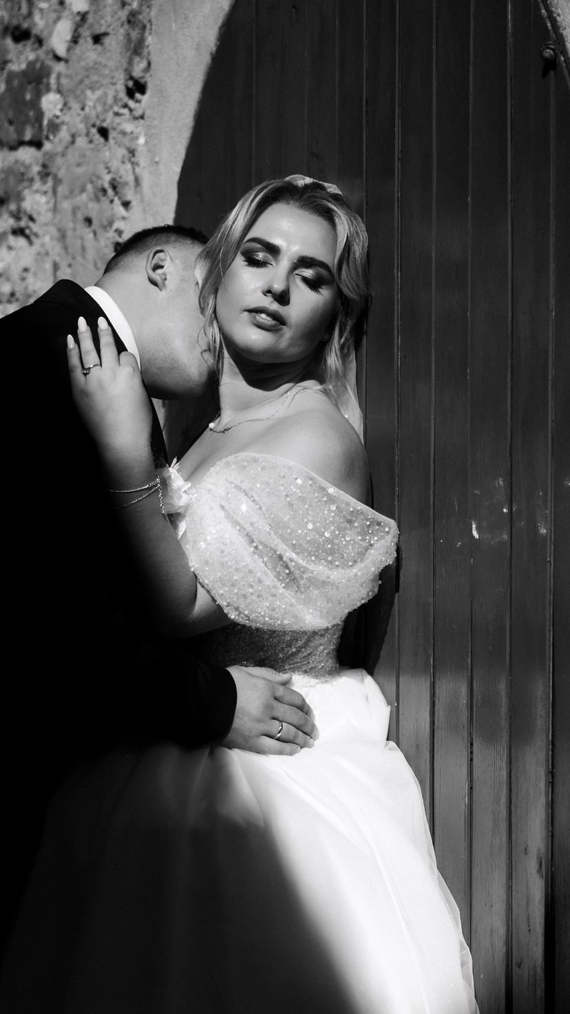 Bride and groom in the stone archway of a historic villa — cinematic black and white